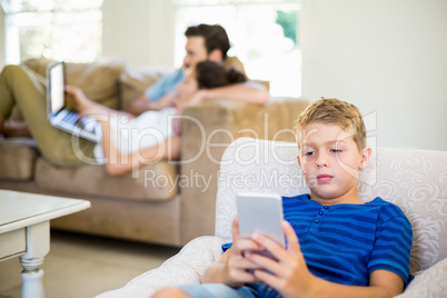 Boy sitting on sofa and using mobile phone