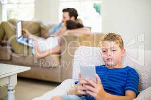 Boy sitting on sofa and using mobile phone