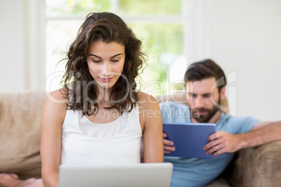 Young couple using digital tablet and laptop