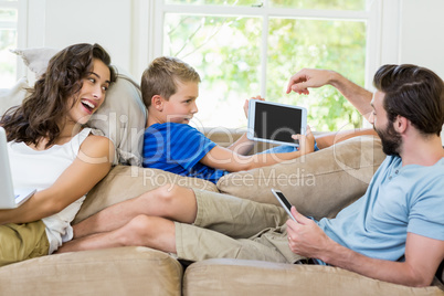 Parents and son using a laptop, tablet and phone