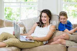 Mother and son sitting on sofa and using laptop