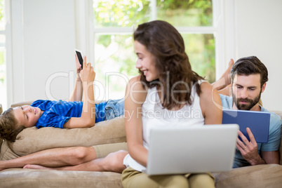 Parents and son using a laptop, tablet and phone