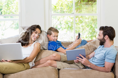 Parents and son using a laptop, tablet and phone