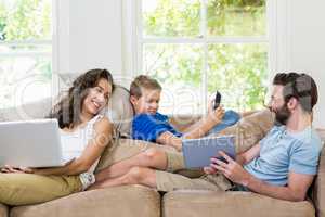 Parents and son using a laptop, tablet and phone