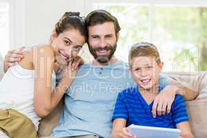 Portrait of parents and son sitting on sofa with arm around