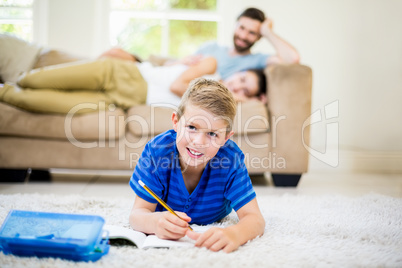 Portrait of boy doing homework in living room