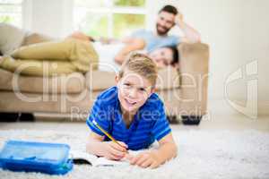 Portrait of boy doing homework in living room