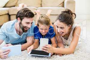 Parents using digital tablet and mobile phone in living room