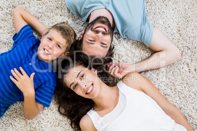 Portrait of parents and son lying on rug