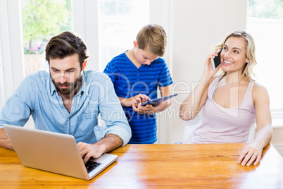 Parents and son using a laptop, tablet and phone