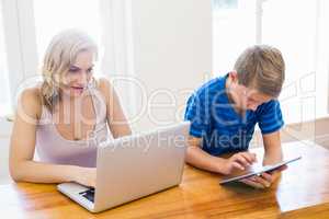 Happy mother and son using laptop and digital tablet