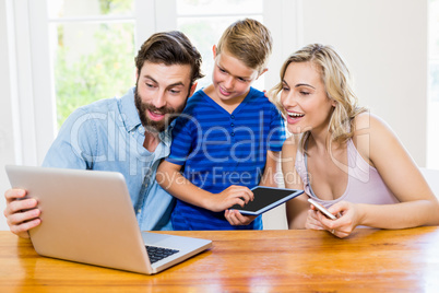 Parents and son using a laptop, tablet and phone