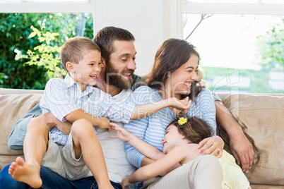 Parents and kids sitting on sofa and having fun