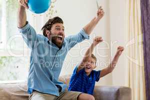 Excited father and son watching television