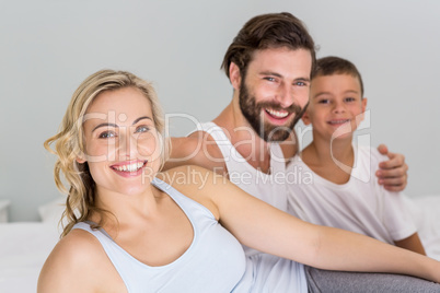 Portrait of parents and son sitting on bed in bedroom