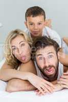 Portrait of parents and son lying on bed and having fun