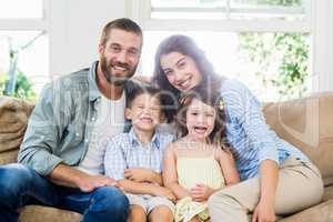 Portrait of parents and kids sitting on sofa in living room