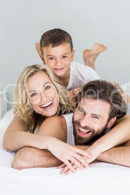 Portrait of parents and son lying on bed in bedroom