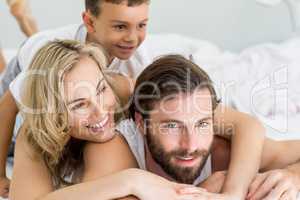 Parents and son lying on bed in bedroom