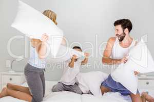 Parents and son having fun on bed in bedroom