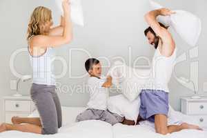 Parents and son having fun on bed in bedroom