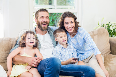 Family and son sitting on sofa and watching television