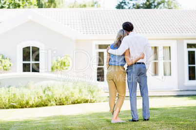 Rear view of couple standing with arm around
