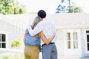 Rear view of couple standing with arm around