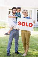 Family standing outside home with sold sign