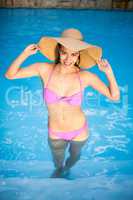 Beautiful woman in bikini standing in swimming pool