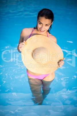 Beautiful woman in bikini standing in swimming pool