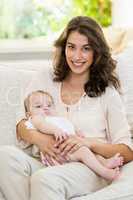 Mother holding her baby on lap in living room