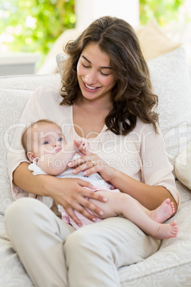 Mother holding her baby on lap in living room