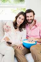 Couple sitting on sofa watching television