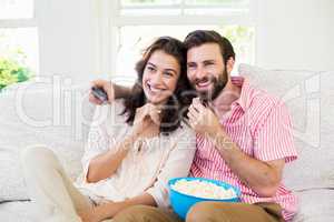 Couple sitting on sofa watching television