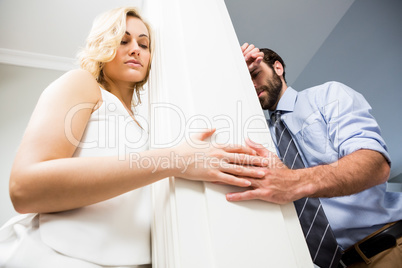 Upset couple standing on opposite sides of the wall