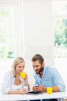 Couple using mobile phone while having coffee