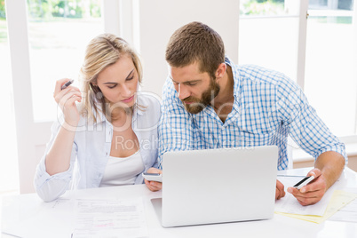 Couple with laptop and mobile phones discussing on bills