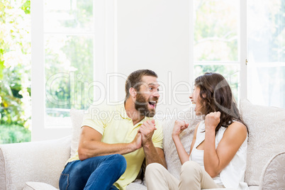 Couple sitting on sofa and having fun in living room