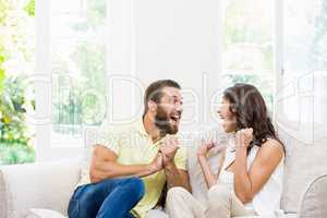 Couple sitting on sofa and having fun in living room