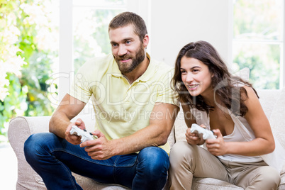 Young couple sitting on sofa and playing video game in living ro