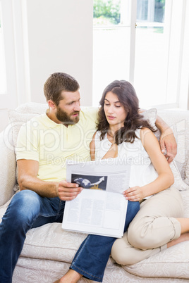 Couple reading newspaper in living room