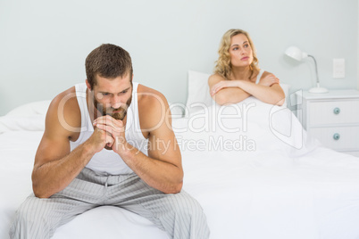 Upset couple ignoring each other after fight on bed