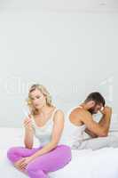 Thoughtful woman looking at pregnancy test on bed