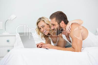 Couple using laptop on bed