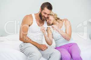 Happy couple looking at pregnancy test on bed