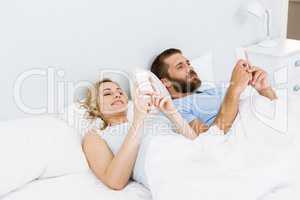 Couple using mobile phone on bed