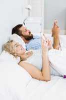 Couple using mobile phone on bed