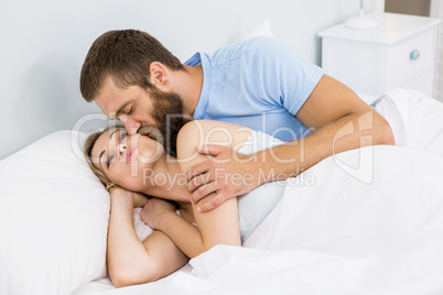 Man kissing woman on her cheek in bed