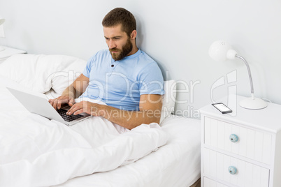 Man using laptop on bed